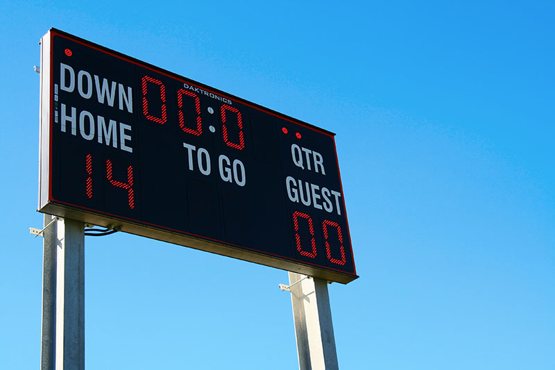A football scoreboard displays Home: 14, Guest: 0 with 0:00 time remaining, under a clear blue sky.